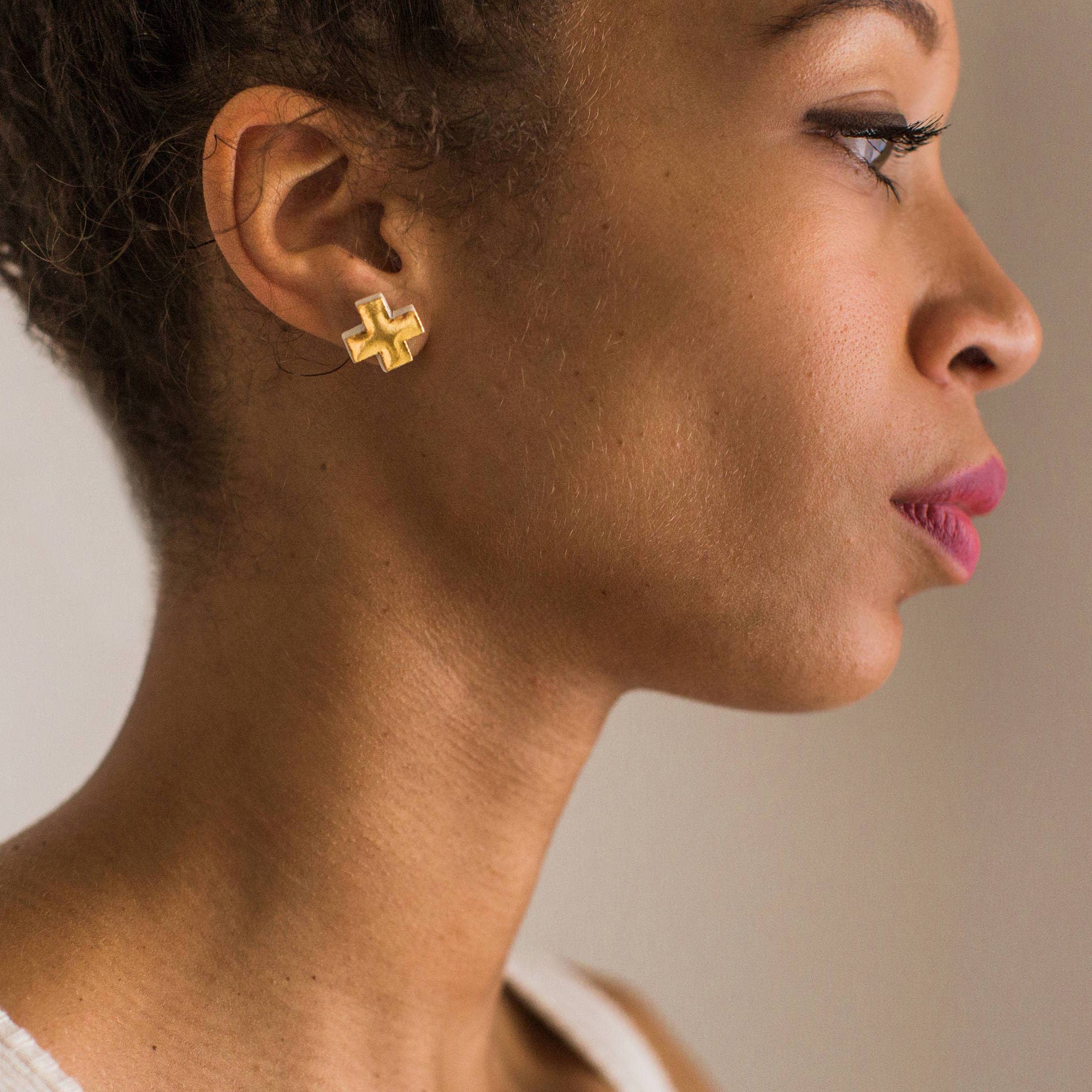 Profile of a woman wearing gold earrings with a neutral background