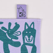 Fabric with green dog pattern on a purple background, featuring a brand tag.