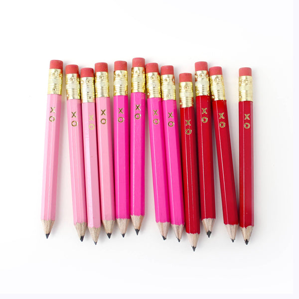 Pink and red pencils with gold accents on a white background