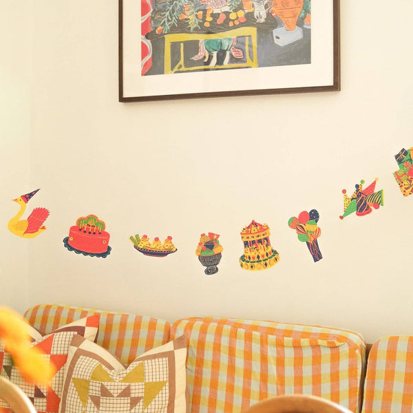 Decorative wall art and stickers on a wall with a sofa and cushions in the foreground.