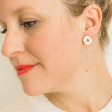 Close-up of a woman wearing a white earring on a plain background