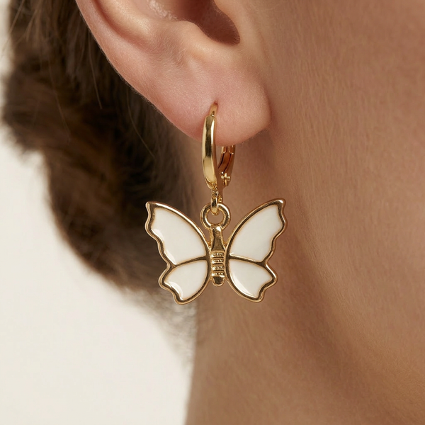 Gold butterfly earring worn on an ear with a neutral background