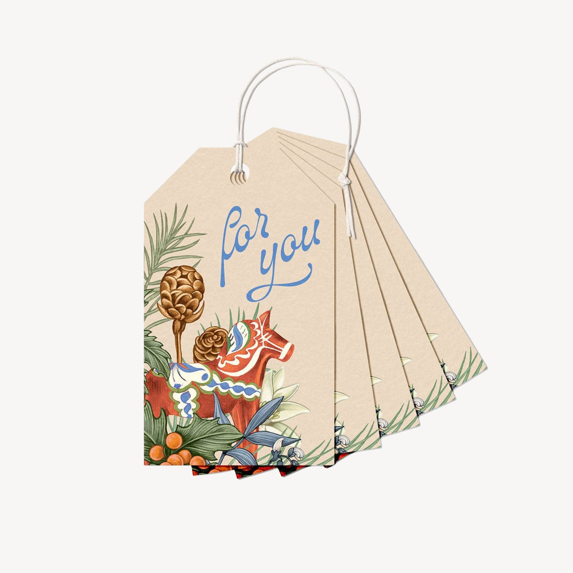 Gift tags with holiday foliage and a toy horse on a plain background.