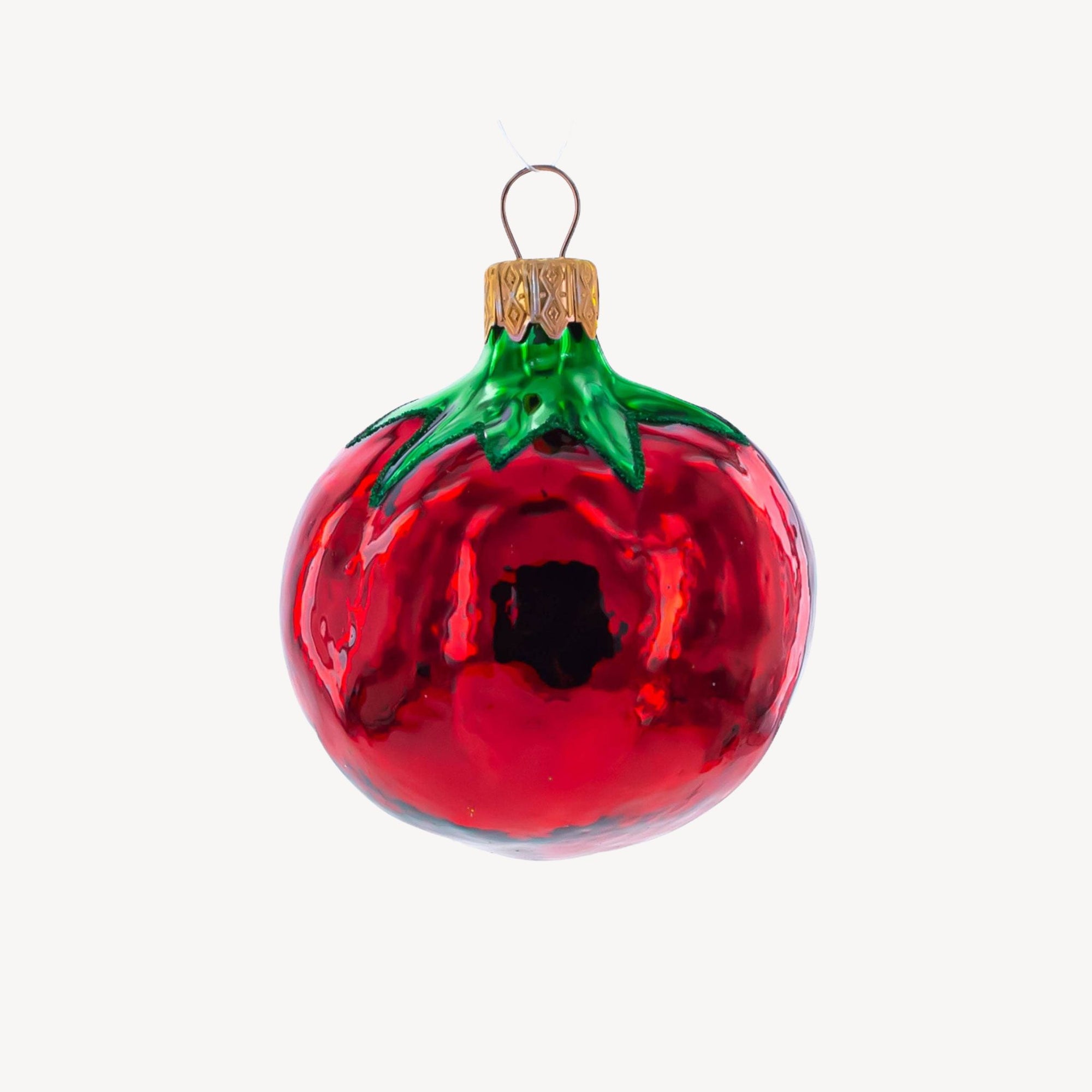 Glass tomato ornament on a plain background.