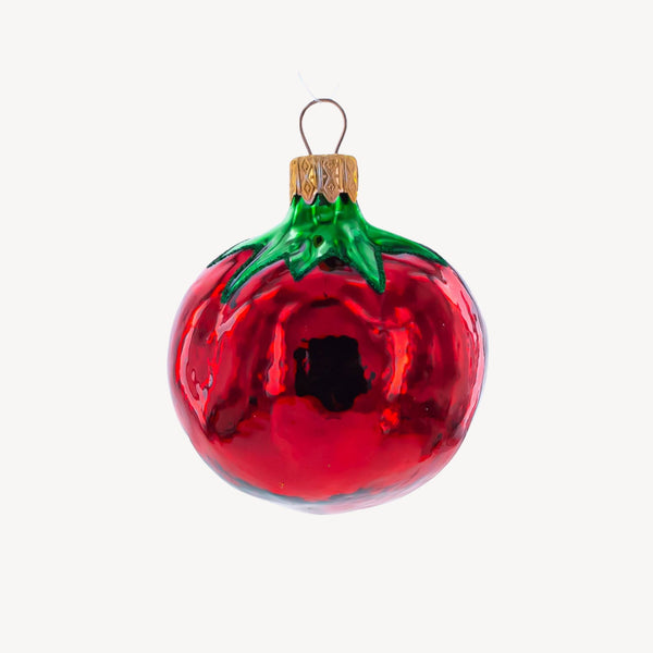 Glass tomato ornament on a plain background.