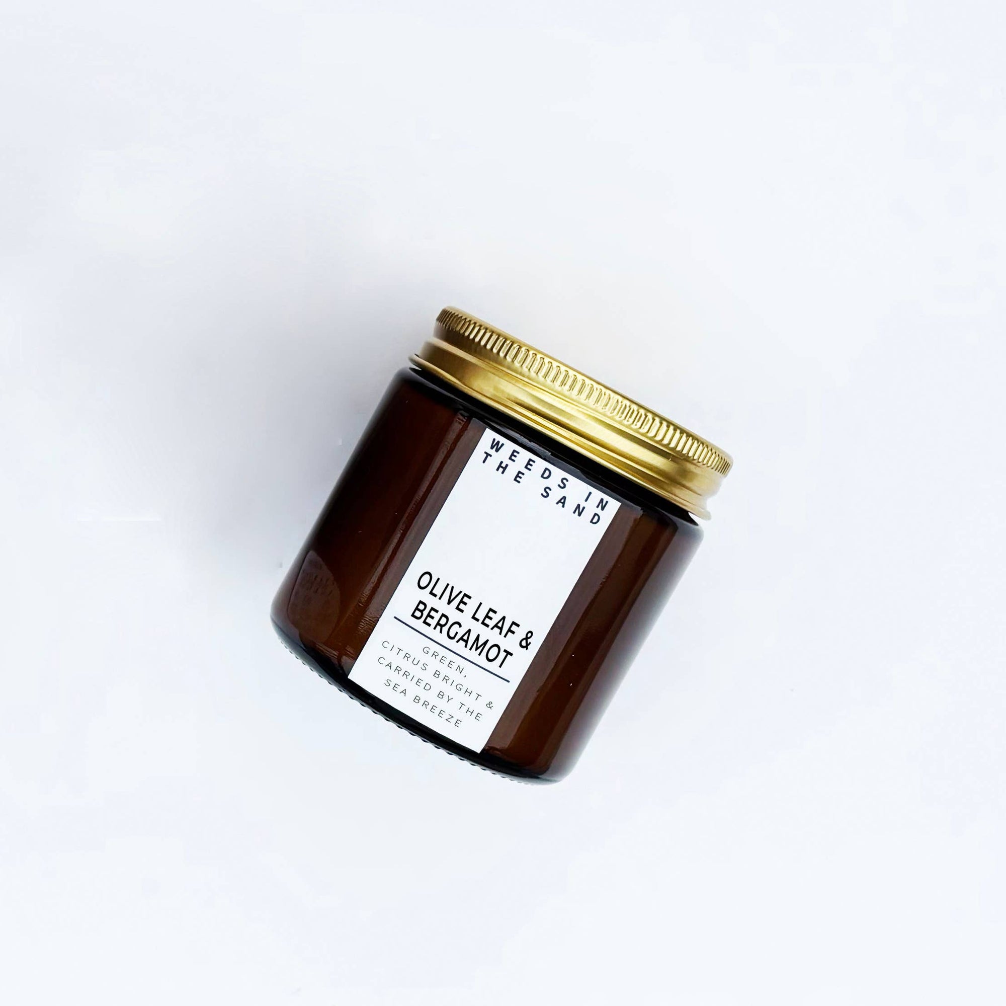 Brown candle jar with gold lid and white label on a white background