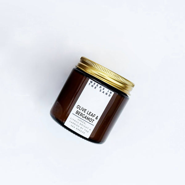 Brown candle jar with gold lid and white label on a white background