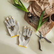 Gardening gloves with bee design on a table with plants and tools