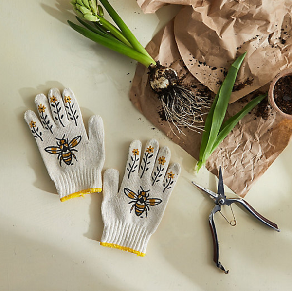 Gardening gloves with bee design on a table with plants and tools