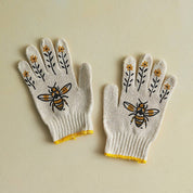 Pair of gloves with bee and flower designs on a beige background
