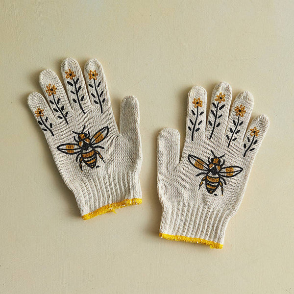 Pair of gloves with bee and flower designs on a beige background