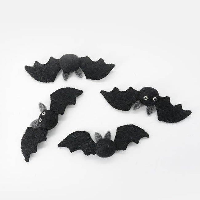 Four black felt bat decorations with small white eyes and gray wings, arranged on a plain white background.