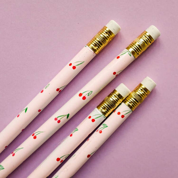Four pink pencils with cherry designs on a purple background