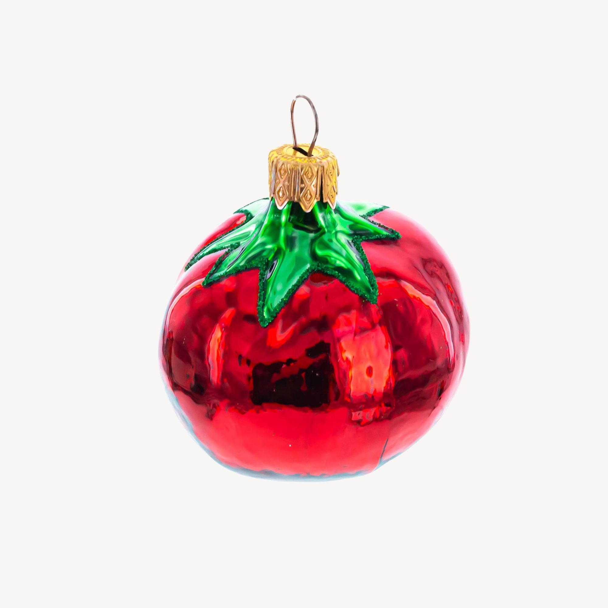 Glass tomato ornament on a plain background.