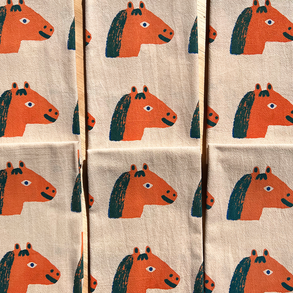 Pattern of orange horse heads on a beige background