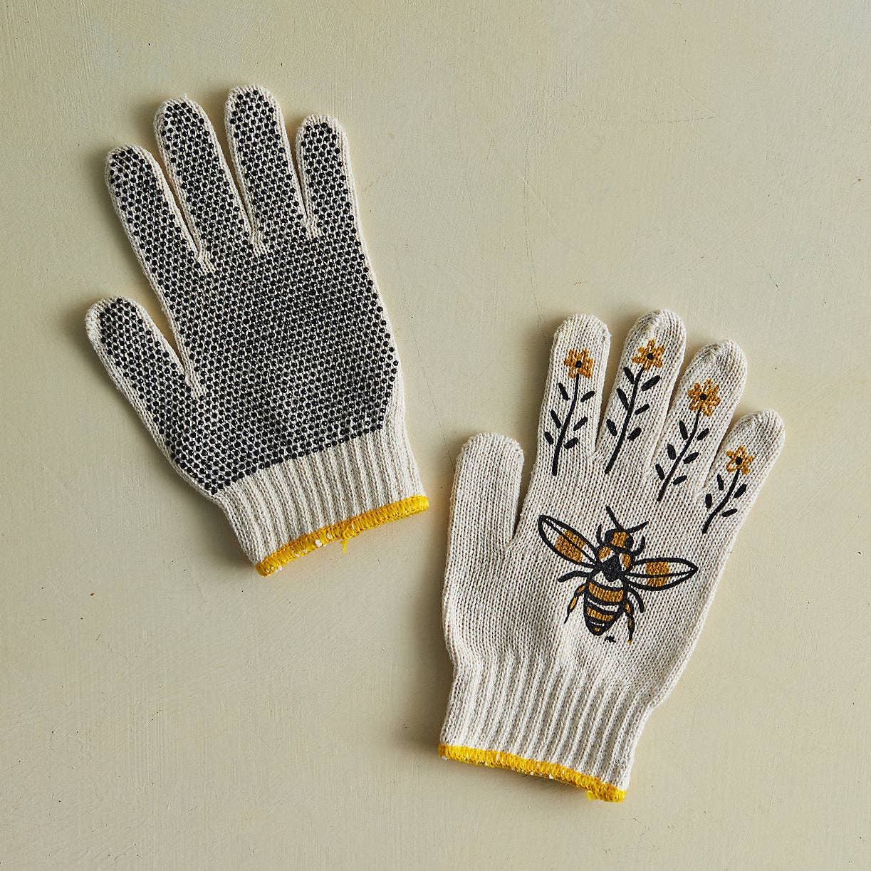 Pair of gloves with textured palm and decorative design on a beige background
