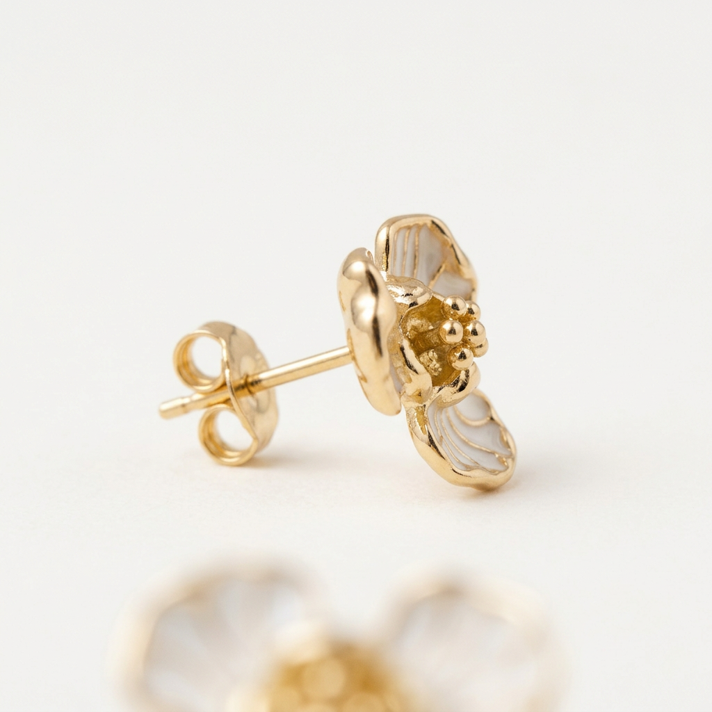 Gold earrings with a white stone on a light background