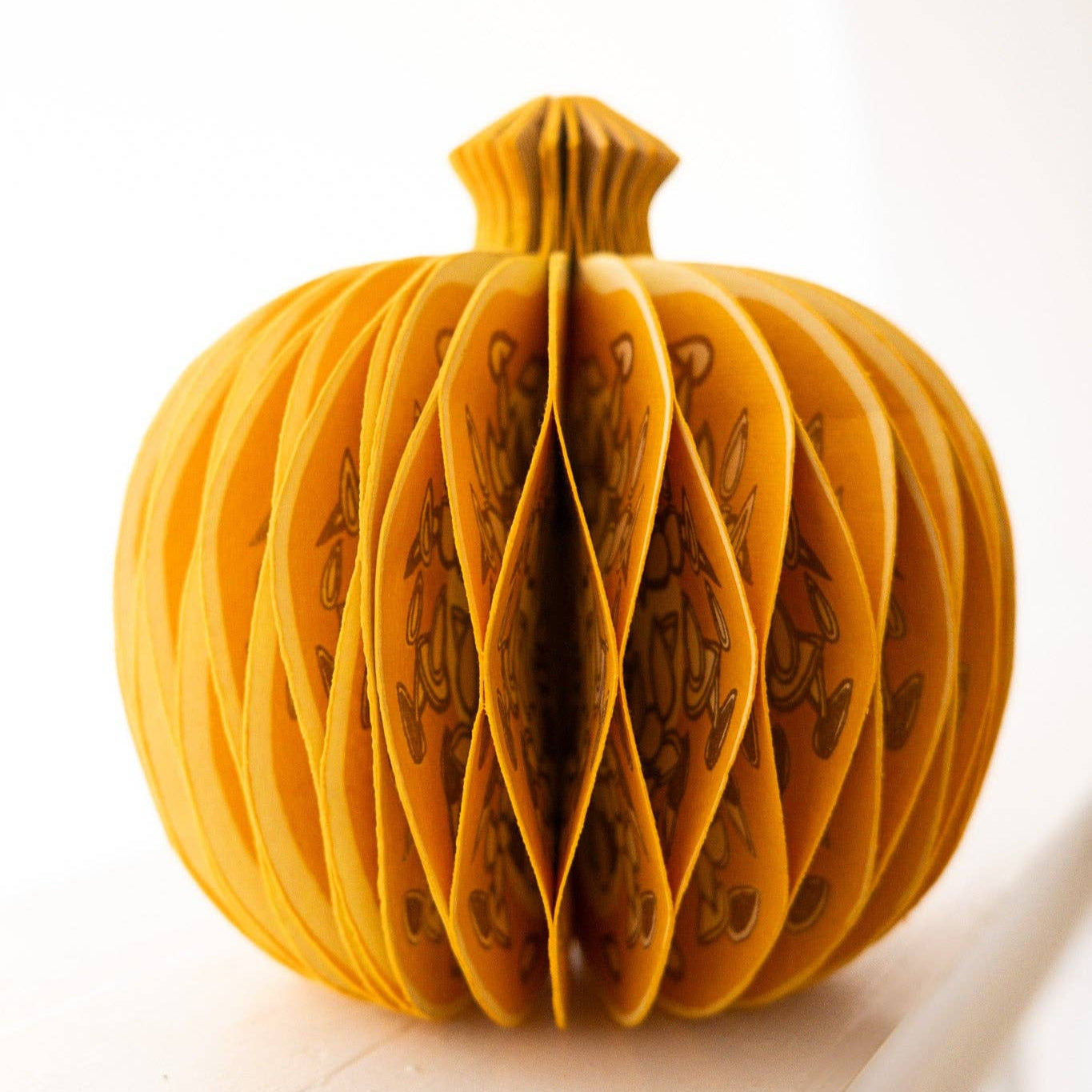 Yellow paper pumpkin with cut-out design on a white background