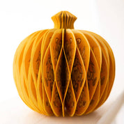 Yellow paper pumpkin with cut-out design on a white background