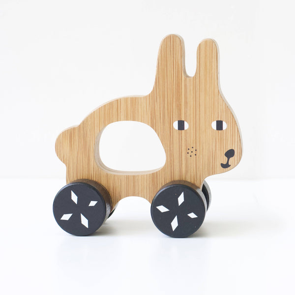 Wooden toy rabbit with black wheels on a white background