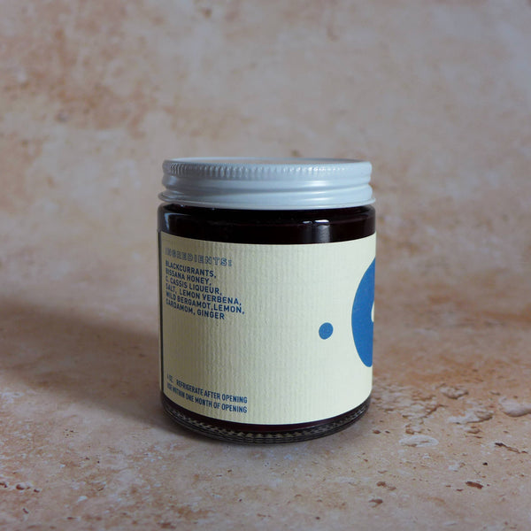 Jar of compote with a label on a textured beige background