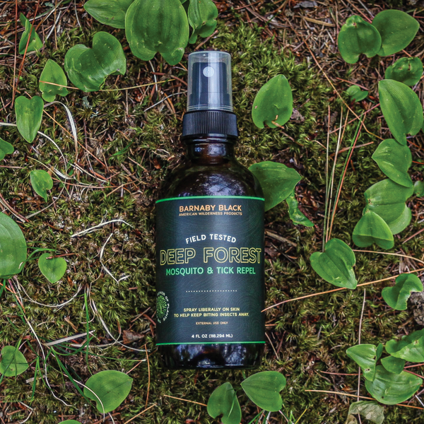 Bottle of Deep Forest Mosquito & Tick Repel on a natural background with green leaves.
