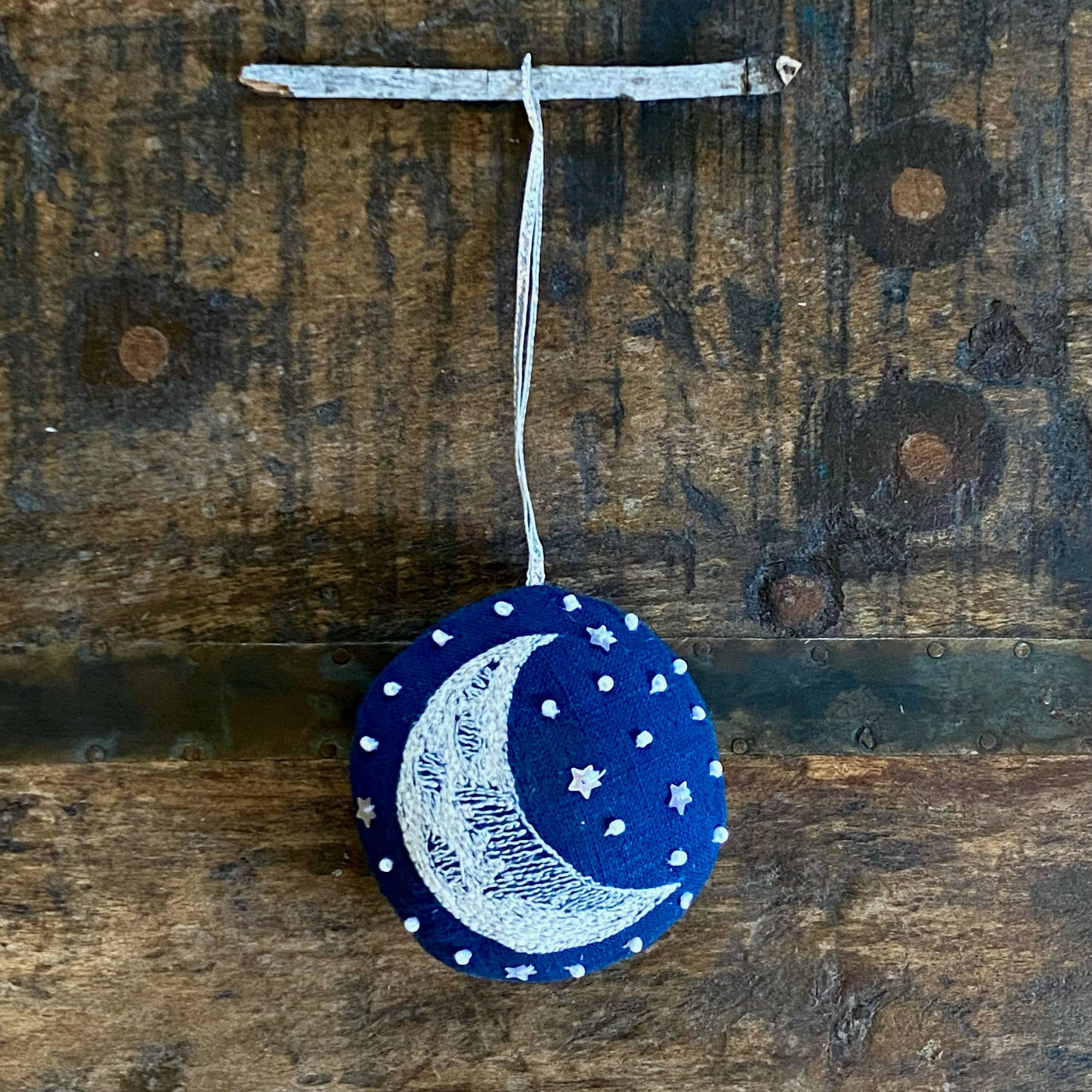 Decorative ornament with moon and star design on a wooden surface