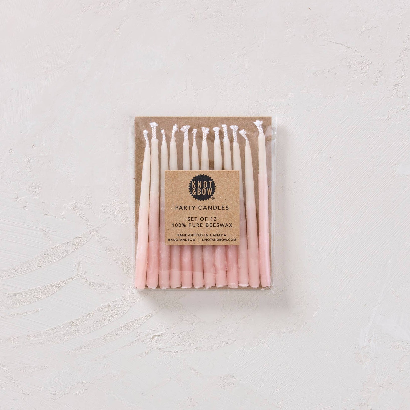 Pack of pink candles with a cardboard label on a white background
