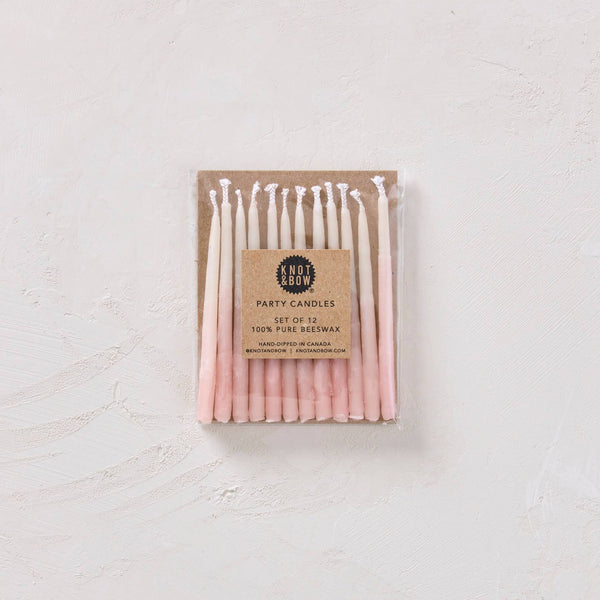 Pack of pink candles with a cardboard label on a white background