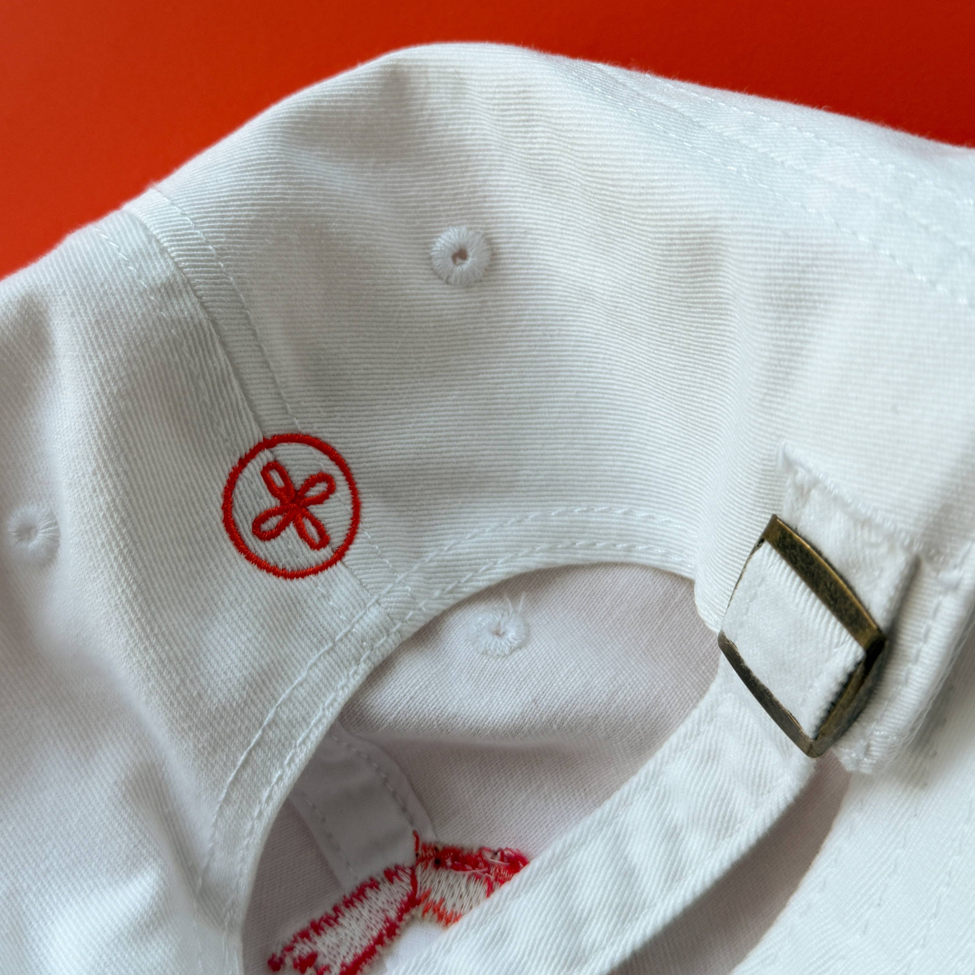 White cap with red logo on a red background