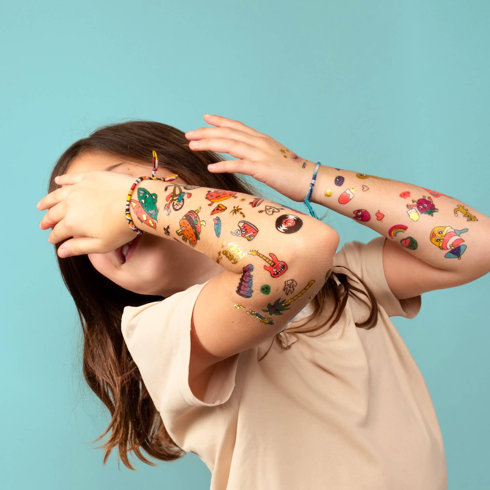 A child with a series of dinosaur themed temporary tattoos on both arms.