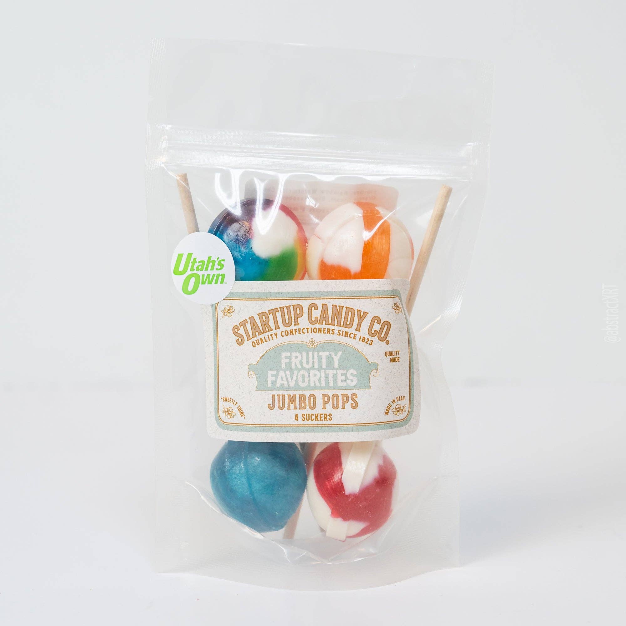 A clear stand-up pouch containing four jumbo pops lollipops in assorted colors, with a front label reading Startup Candy Co. Fruity Favorites Jumbo Pops.