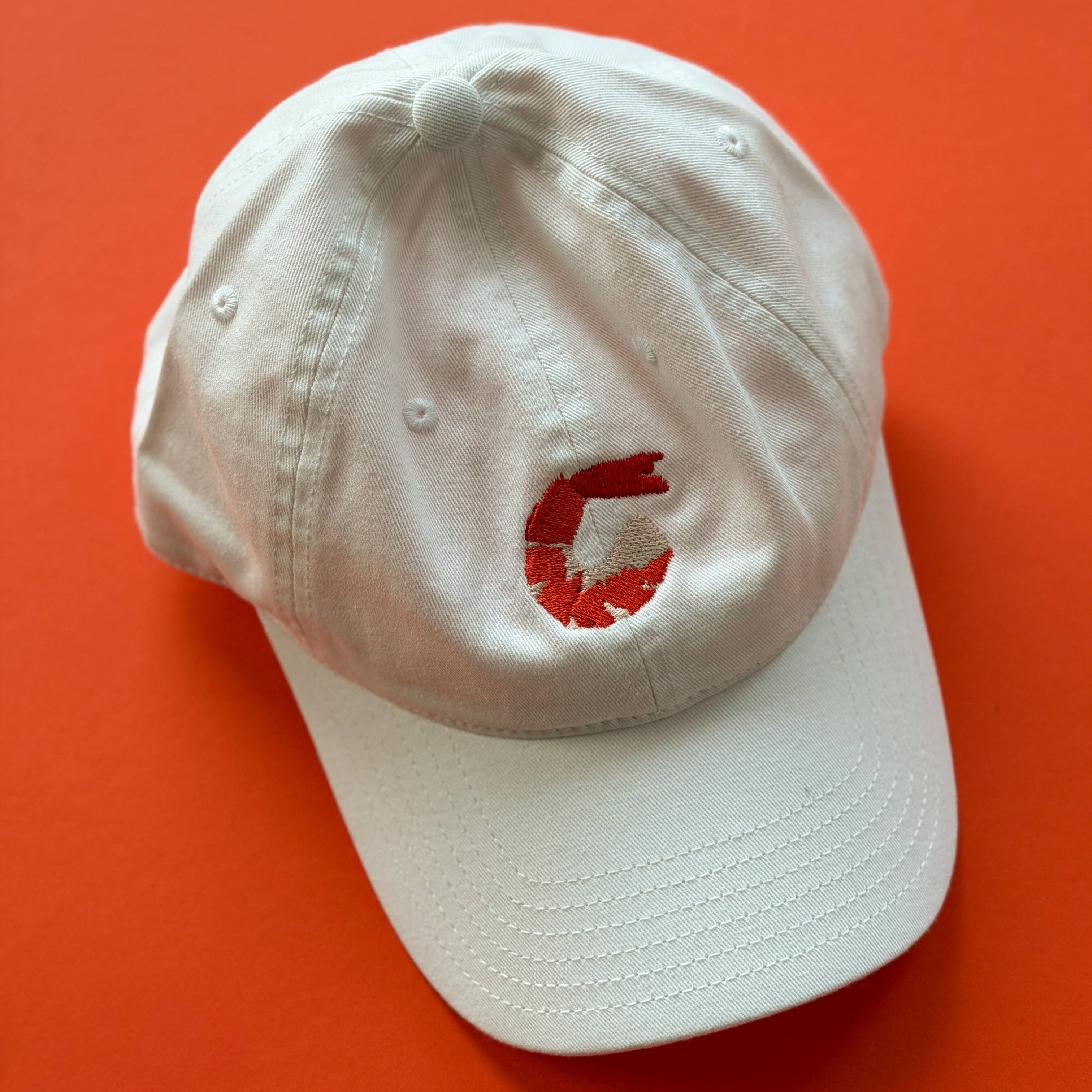 White cap with a red logo on an orange background