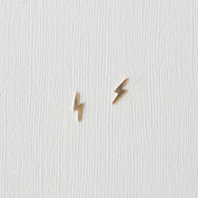 Pair of gold lightning bolt earrings on a light gray background