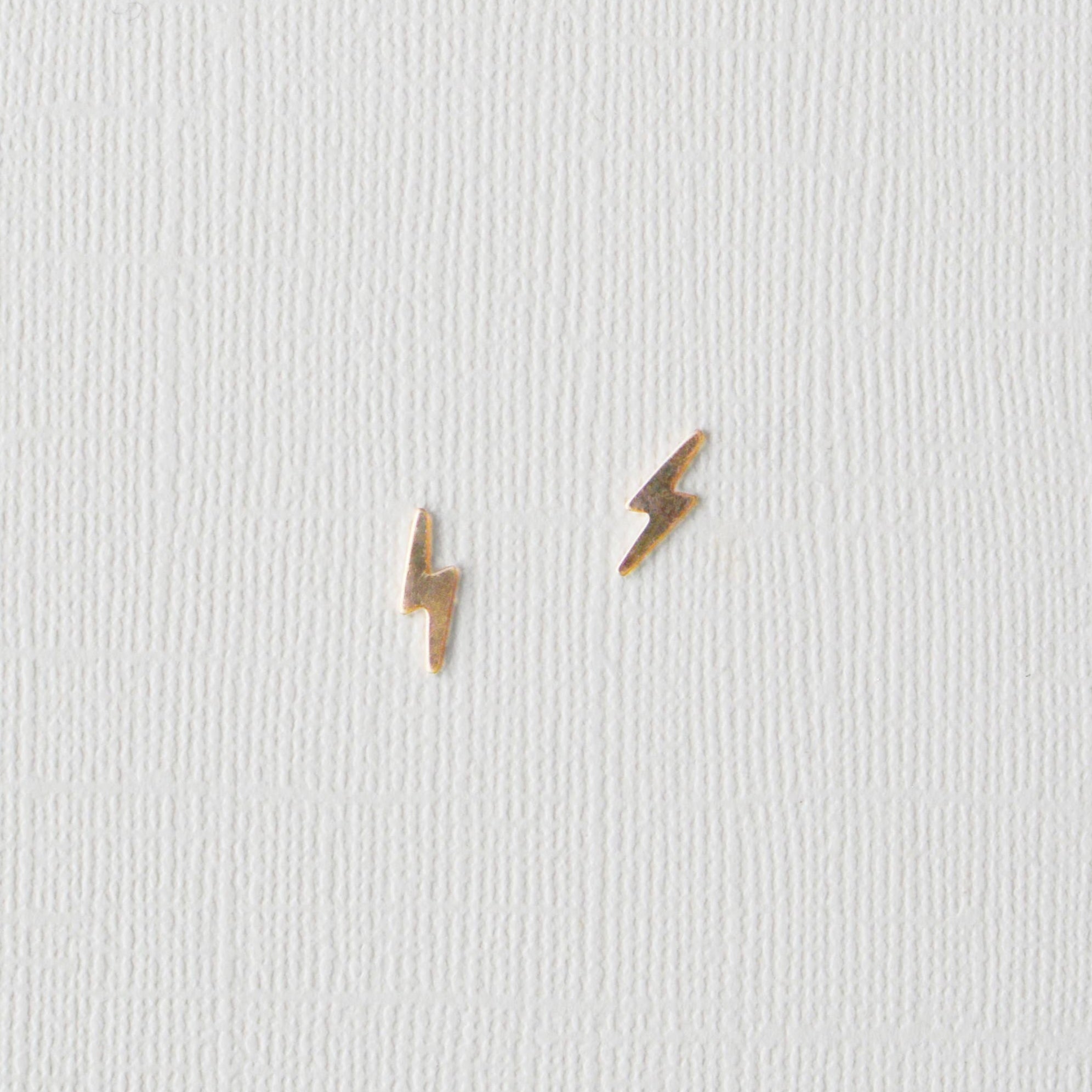 Pair of gold lightning bolt earrings on a light gray background