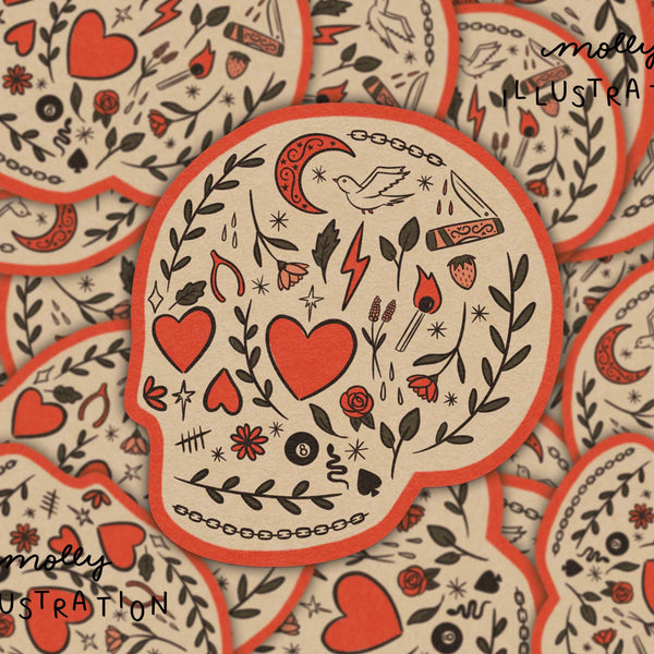 A close-up of multiple overlapping skull-shaped stickers or cards with a tattoo-style illustration. The central piece shows red hearts, black floral and line motifs, and a red border on a warm cream background.