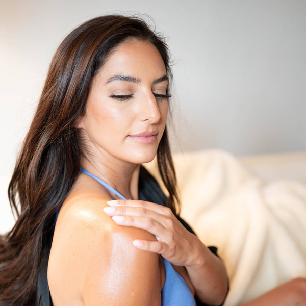 A woman with brown hair rubs her shoulder.