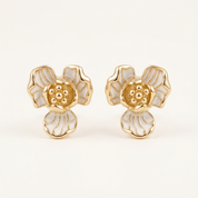 Pair of gold and white floral earrings on a light beige background