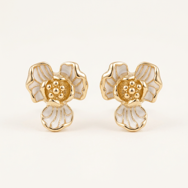 Pair of gold and white floral earrings on a light beige background