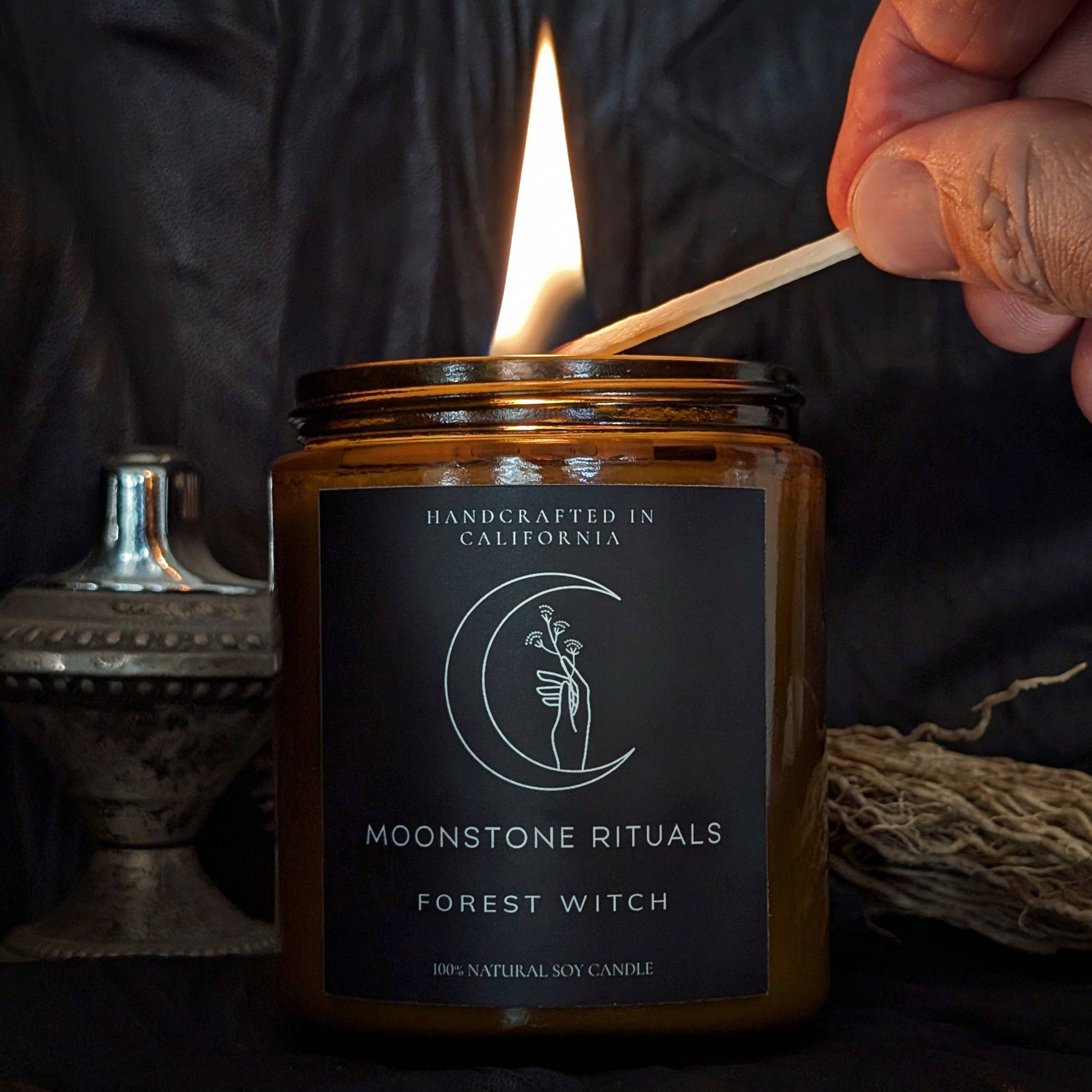 A hand lighting a candle with a match.