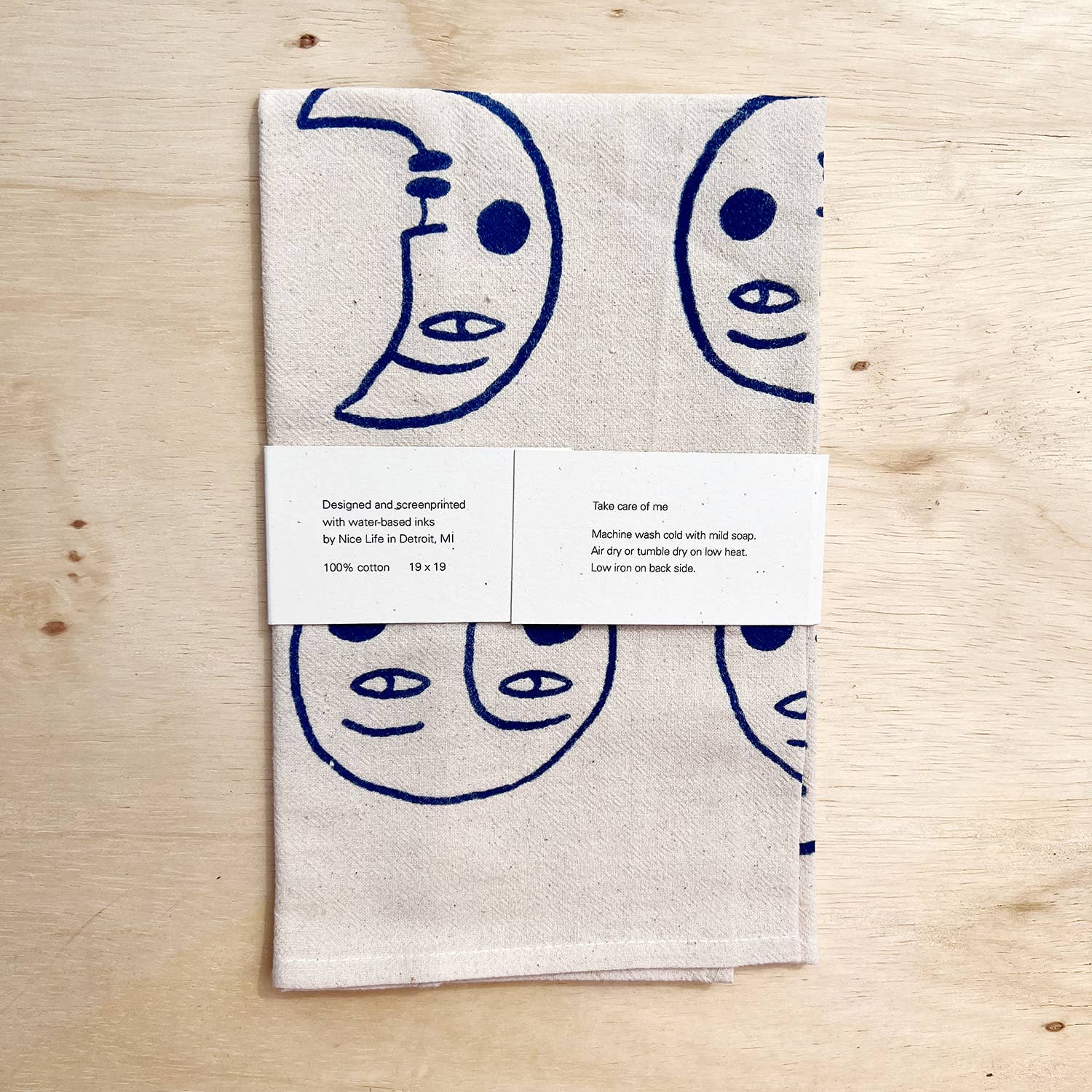 Folded towel with blue crescent moon and face designs on a wooden surface