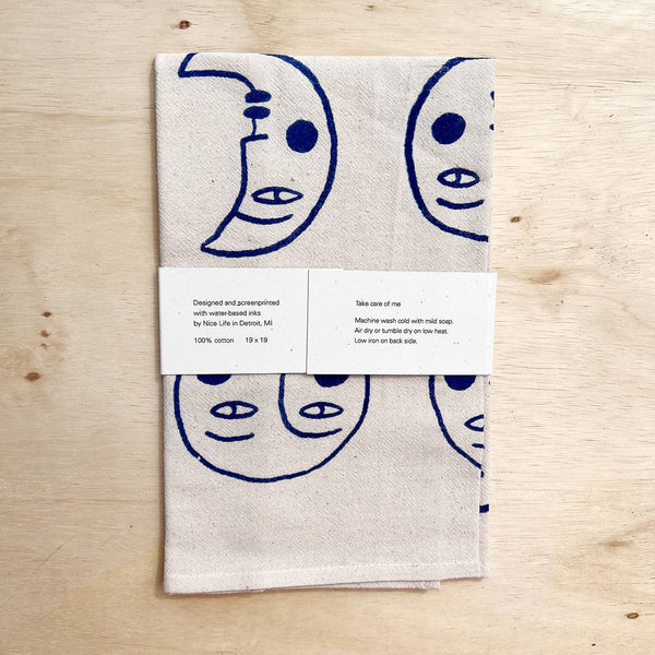 Folded towel with blue crescent moon and face designs on a wooden surface