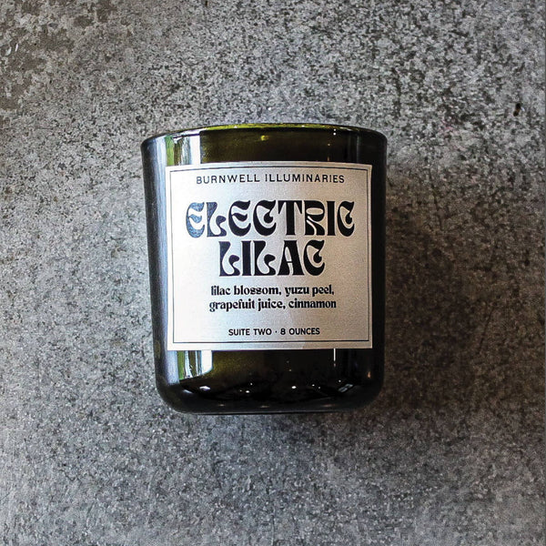 Candle in a glass jar with a label on a gray surface