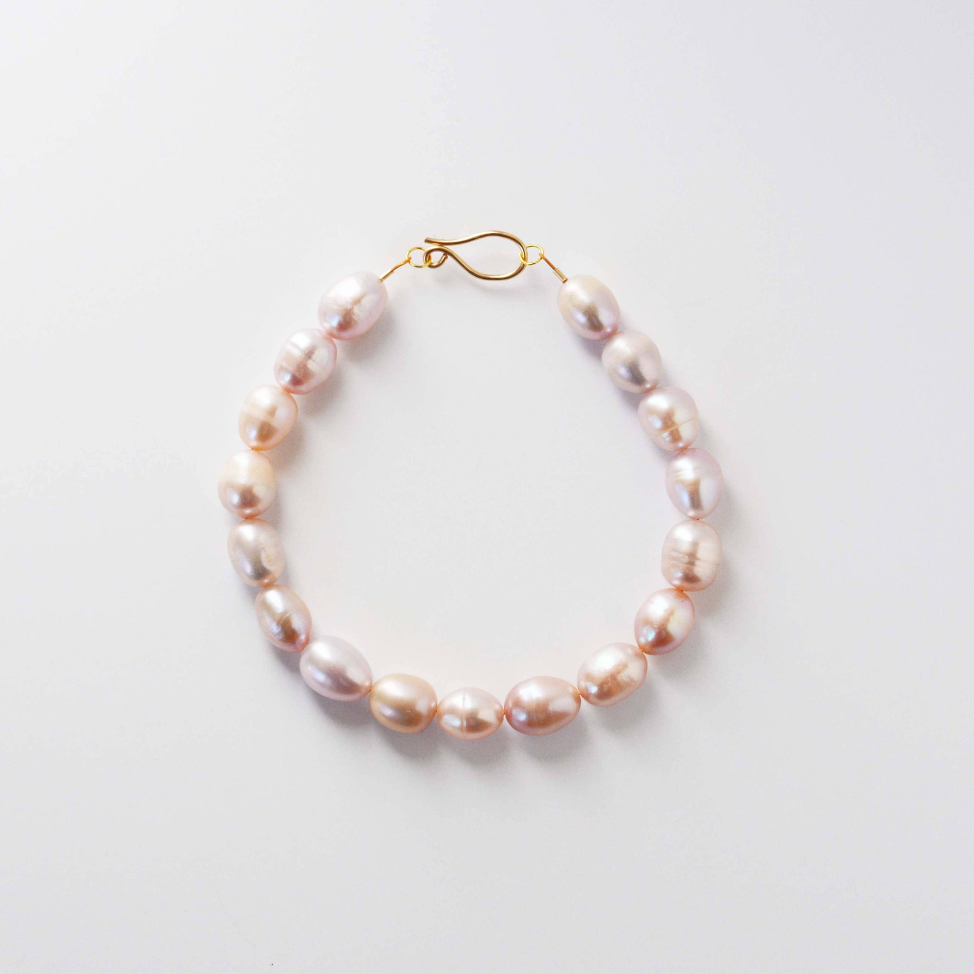 Rose colored pearl bracelet on a light gray background