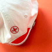 White cap with a red logo on an orange background