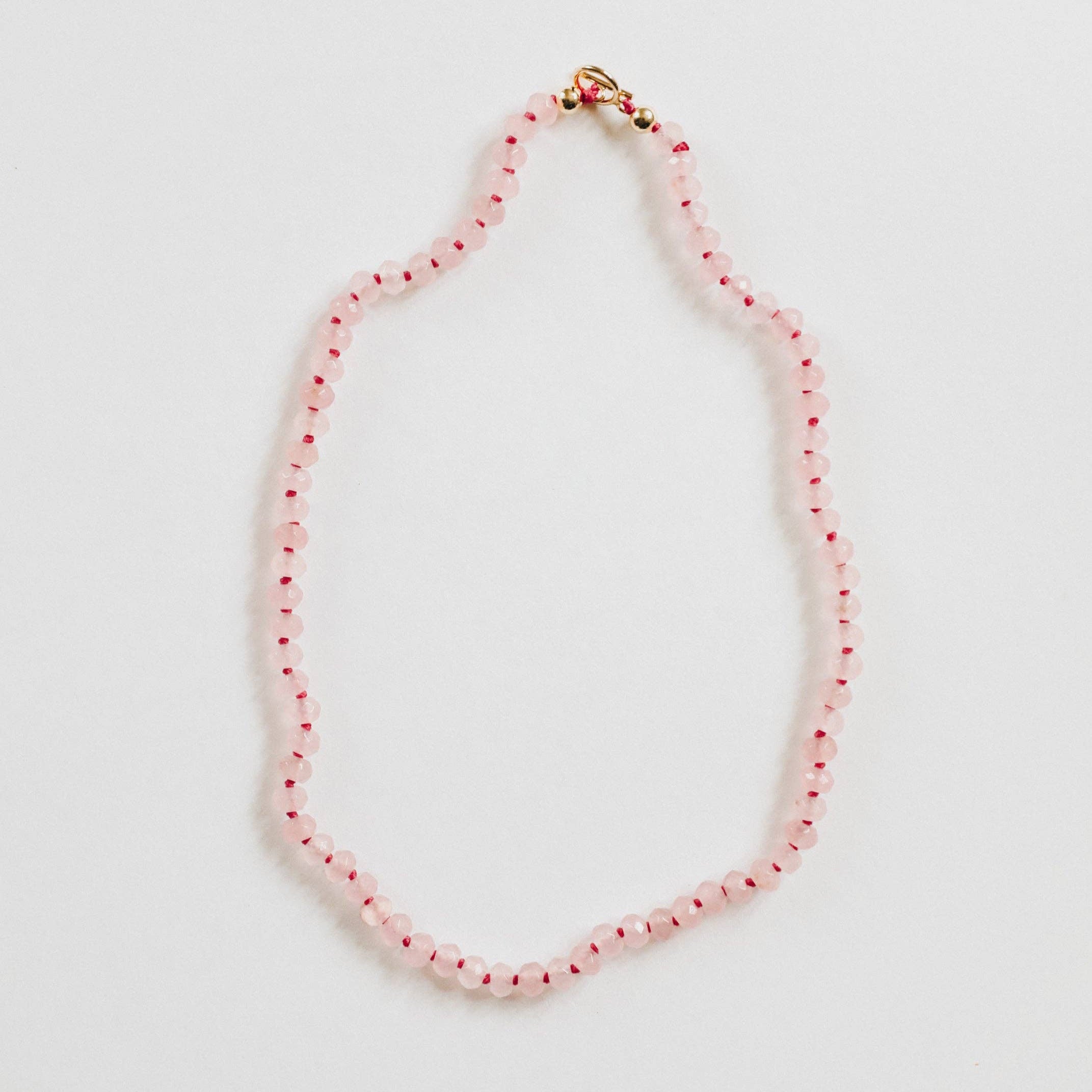 CanyonLeaf rose quartz gemstone necklace with a delicate pendant on a silver chain, displayed on a soft fabric background.