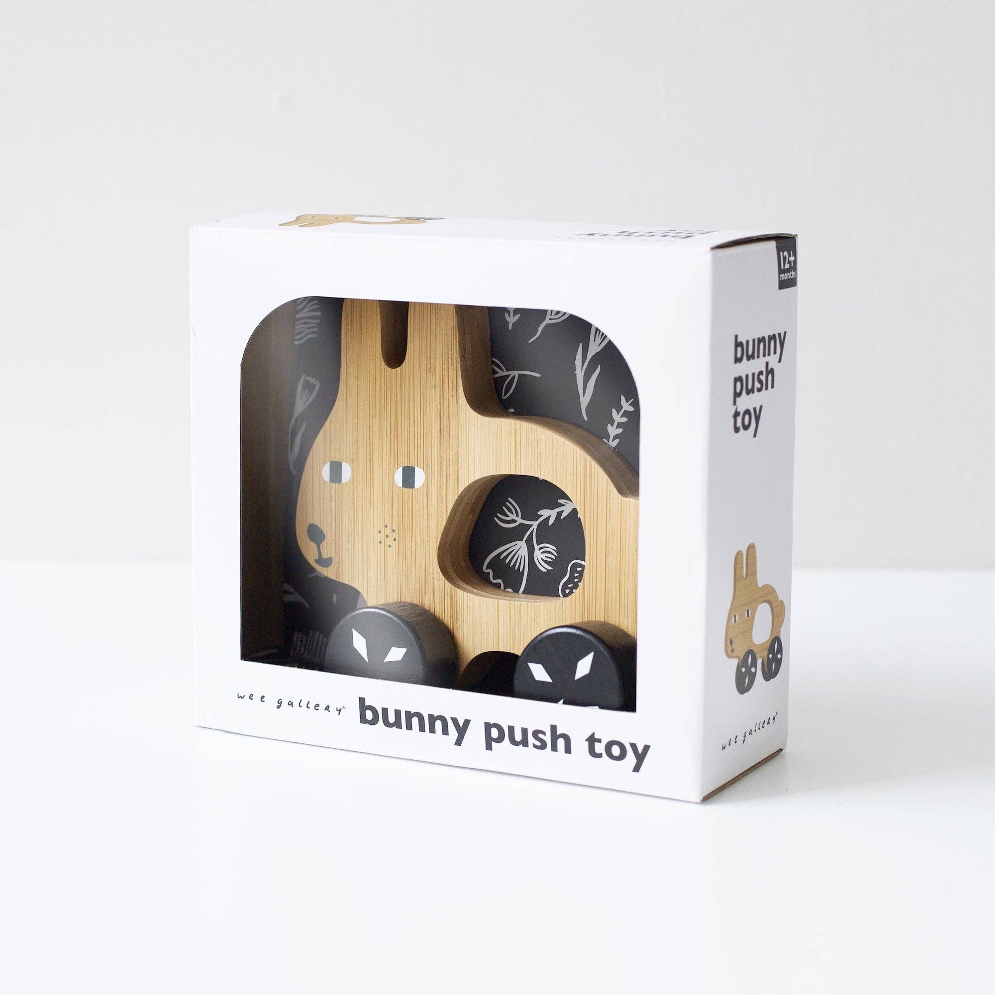 Wooden bunny push toy in a white box packaging on a white background