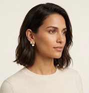 Woman wearing gold earrings with a neutral background