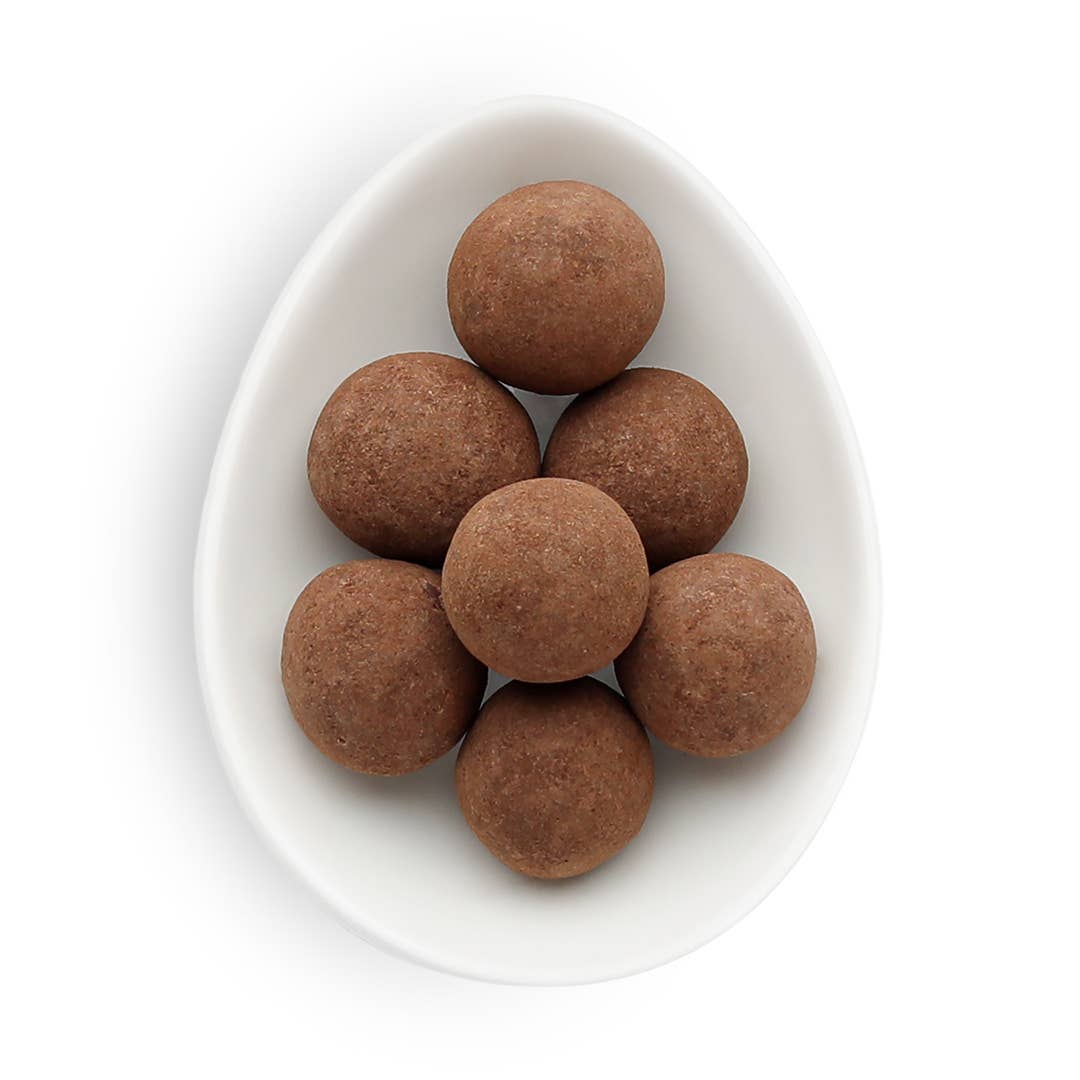 White bowl filled with brown spherical candies on a white background