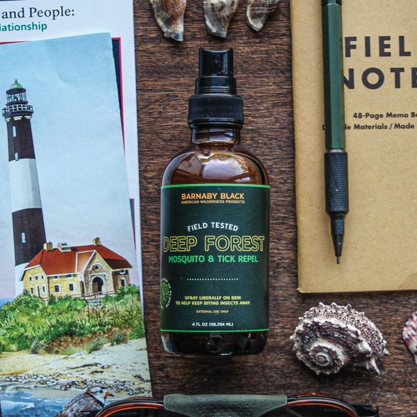 Bottle of 'Deep Forest' mosquito and tick repellent on a wooden surface with sunglasses, notebook, and lighthouse illustration.